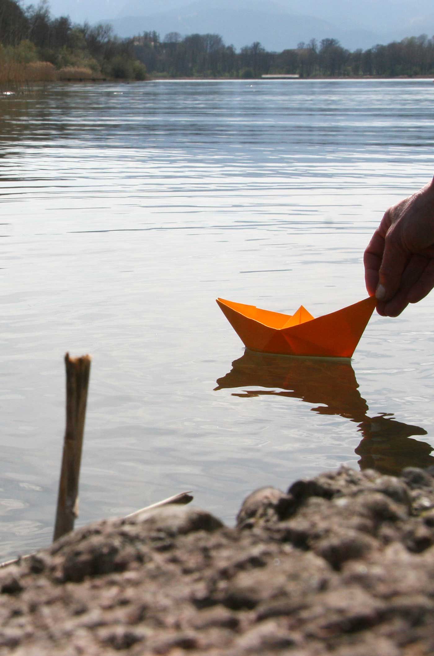 Papierschiffchen wird zu Wasser gelassen